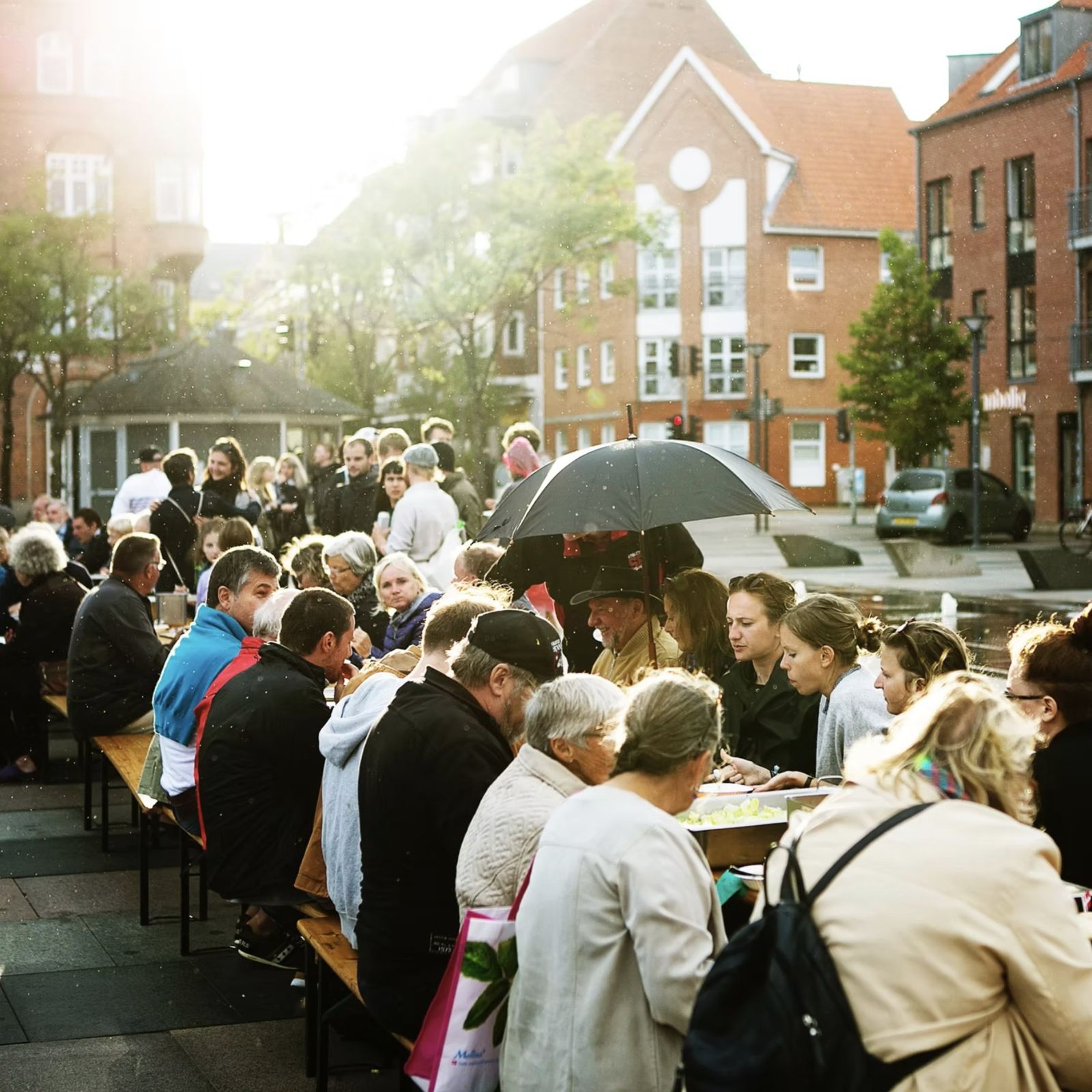 Babette’s Town Feast: neighbours eating together at a long table on Fredericia’s town square in the evening sun