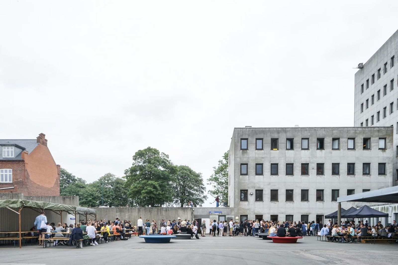 EASA 2017 courtyard in Fredericia: participants eating at long tables and queuing for food beside a concrete building