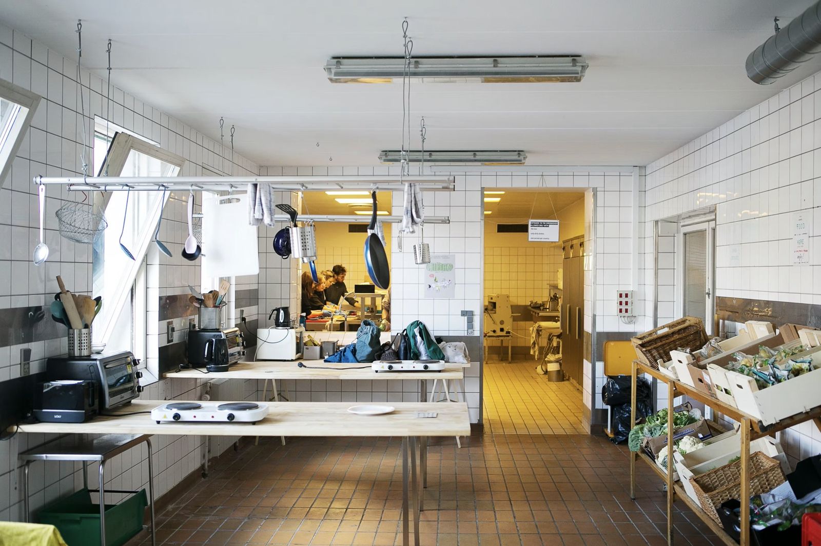 The tiled Fredericia Food Lab kitchen with hot plates on long tables and a produce rack