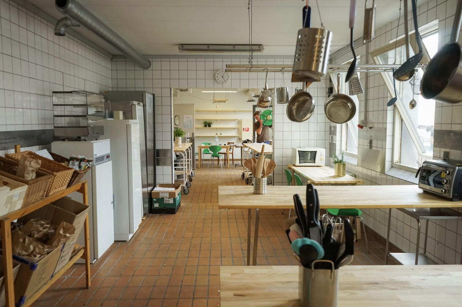 The Fredericia Food Lab kitchen in daylight, with hanging pans and wooden worktables